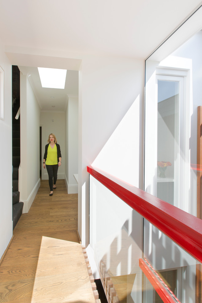 Cette image montre un couloir design de taille moyenne avec un mur blanc et un sol en bois brun.
