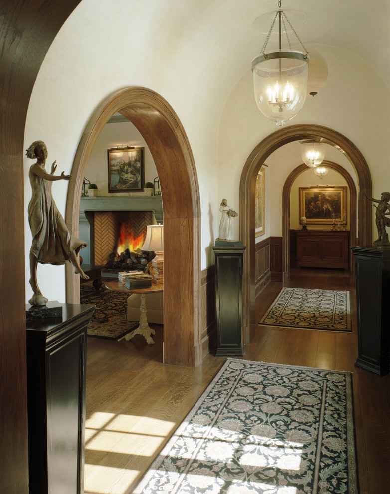 Ejemplo de recibidores y pasillos mediterráneos con suelo de madera en tonos medios y paredes beige