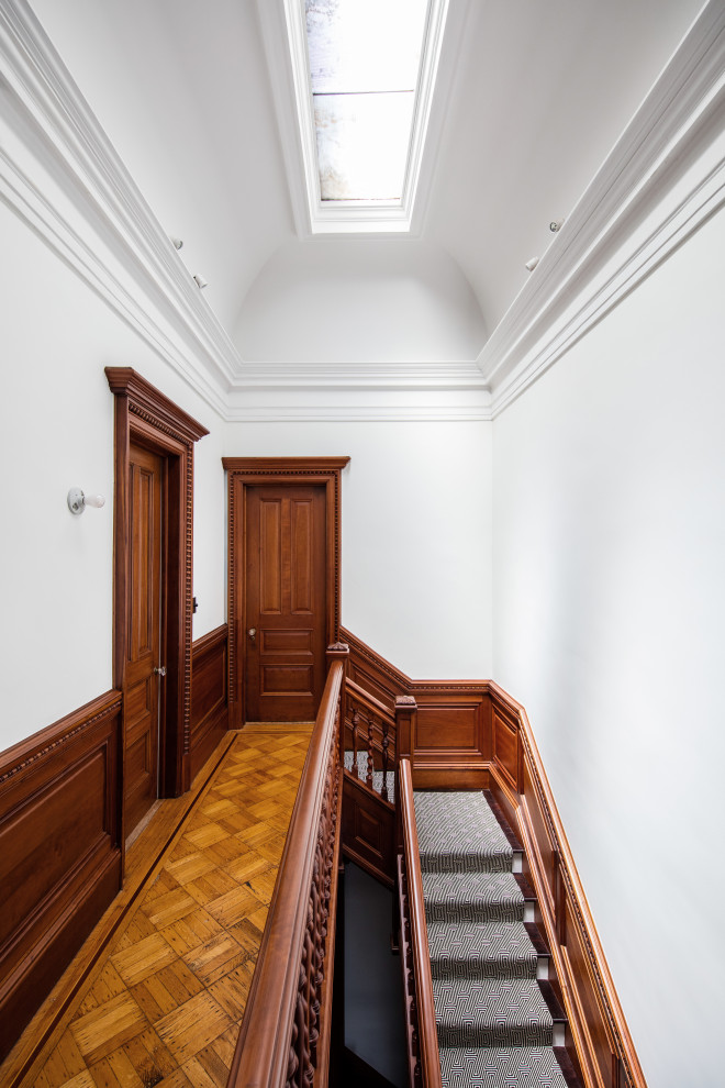 Modelo de recibidores y pasillos modernos de tamaño medio con paredes blancas, suelo de madera en tonos medios y suelo marrón