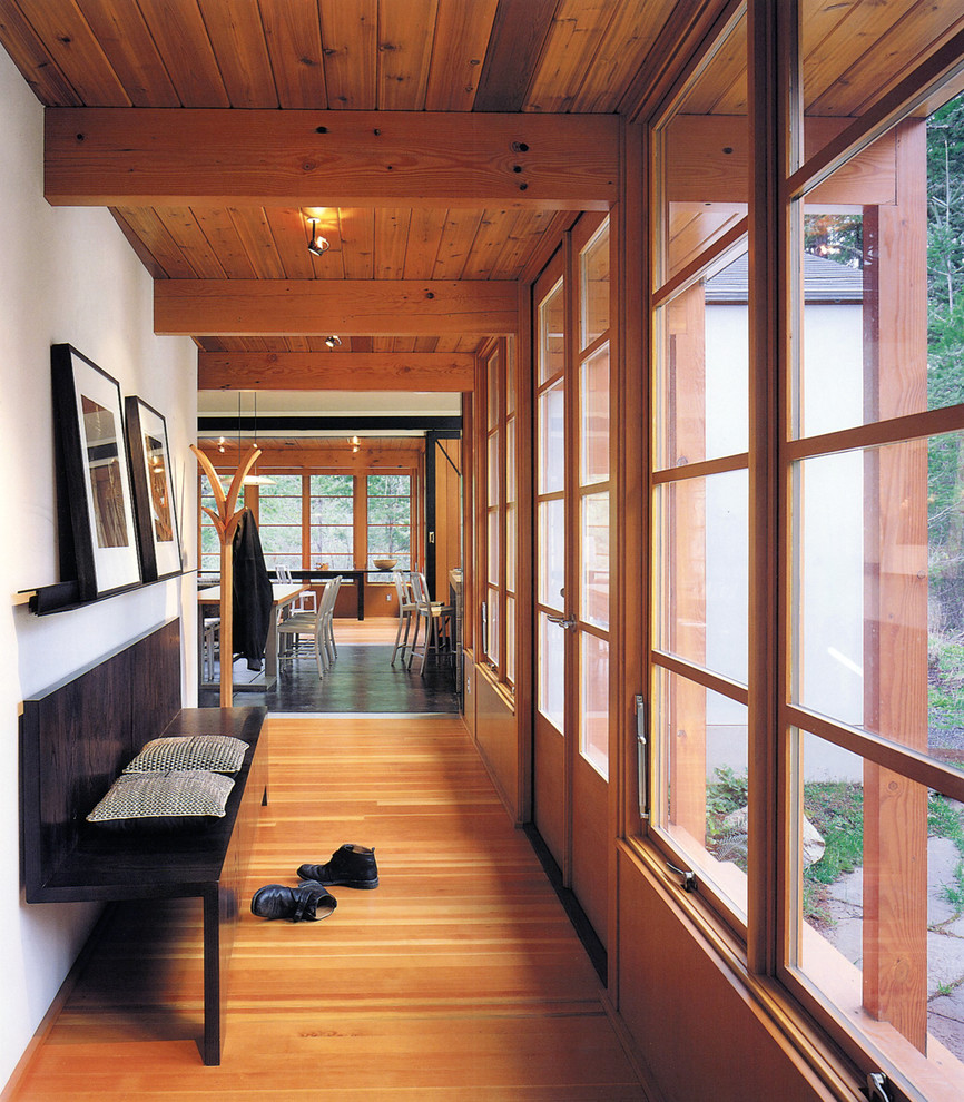 Idées déco pour un couloir contemporain avec un mur blanc et un sol en bois brun.