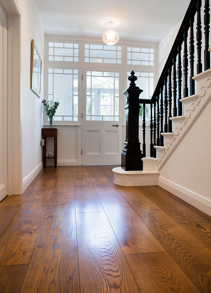 Inspiration for a mid-sized modern dark wood floor hallway remodel in London with white walls