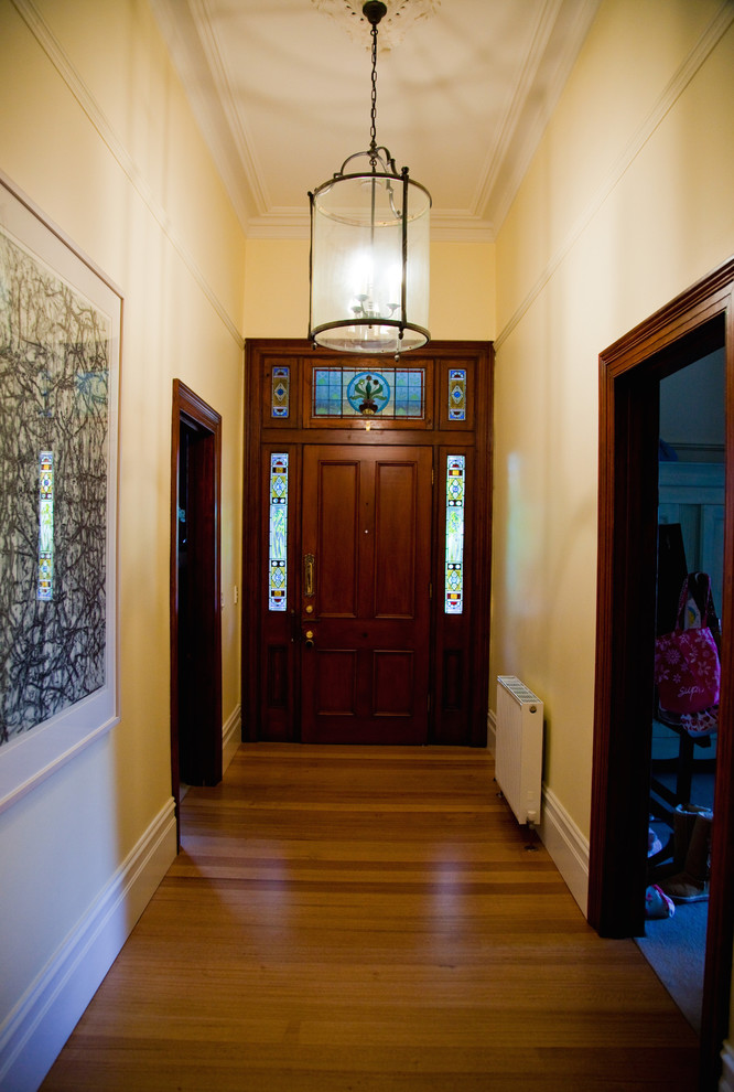 Immagine di un grande ingresso o corridoio vittoriano con pareti gialle e pavimento in legno massello medio