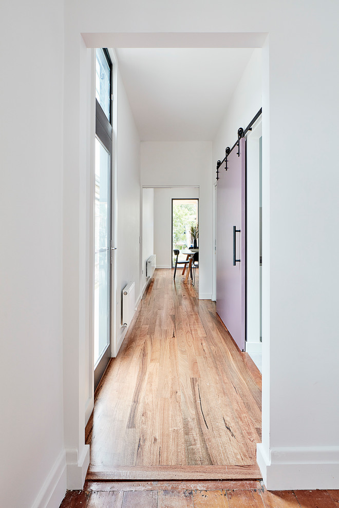 Foto de recibidores y pasillos actuales grandes con paredes blancas, suelo de madera clara, suelo marrón y machihembrado