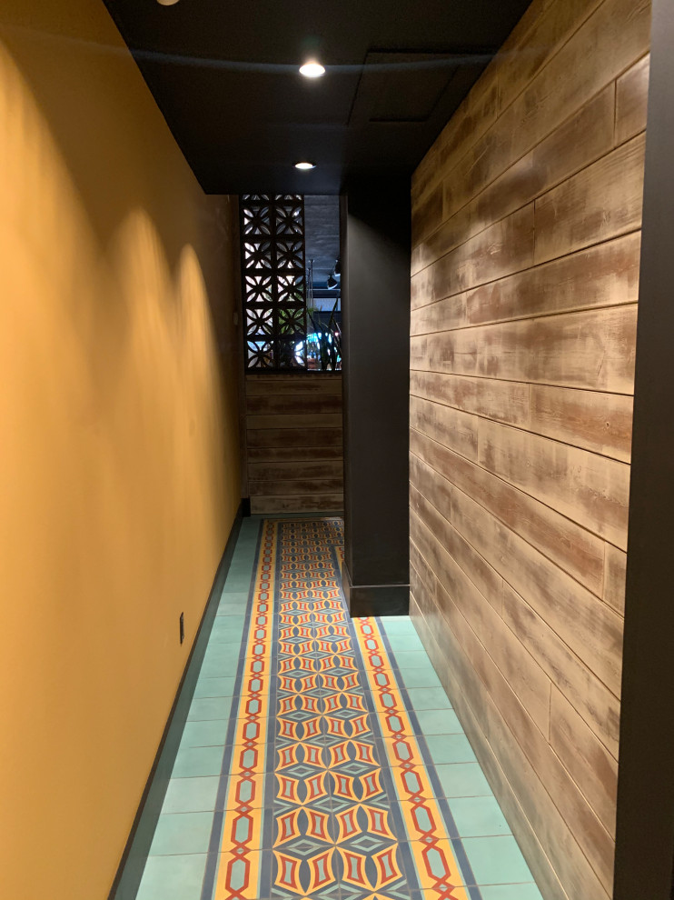 Aménagement d'un couloir éclectique de taille moyenne avec un mur jaune, un sol en carrelage de porcelaine, un sol multicolore et poutres apparentes.
