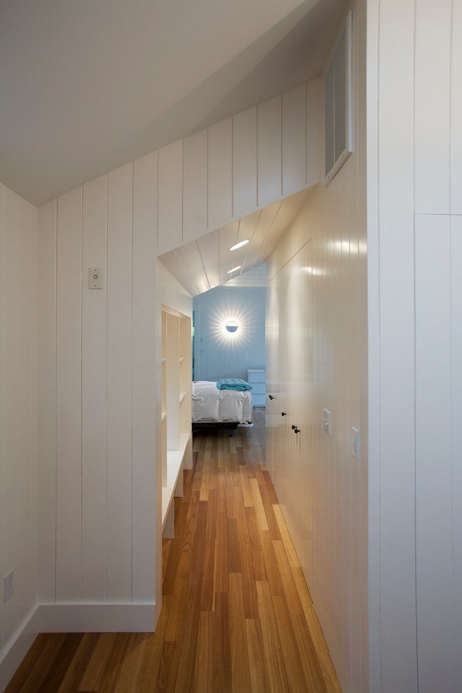 Cette image montre un petit couloir marin avec un mur blanc et un sol en bois brun.