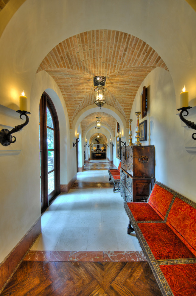 На фото: коридор: освещение в средиземноморском стиле с бежевыми стенами и разноцветным полом с