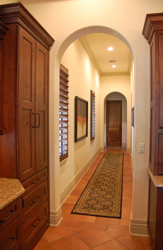 На фото: коридор среднего размера в средиземноморском стиле с белыми стенами и полом из терракотовой плитки с