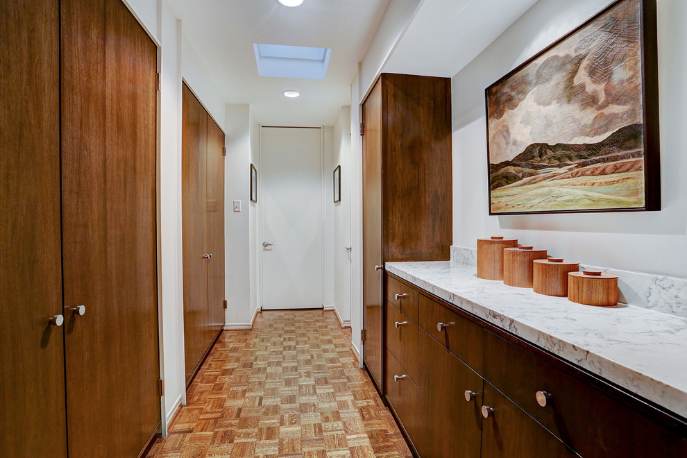 Hallway - mid-sized 1950s medium tone wood floor hallway idea in Houston with white walls