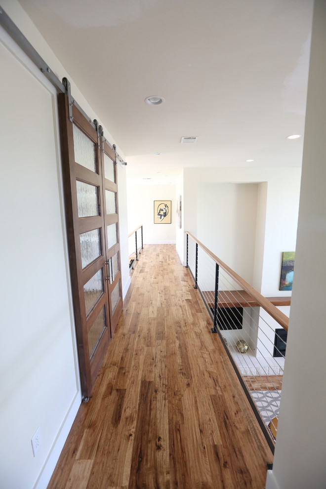 Mid-sized trendy medium tone wood floor and brown floor hallway photo in Dallas with white walls