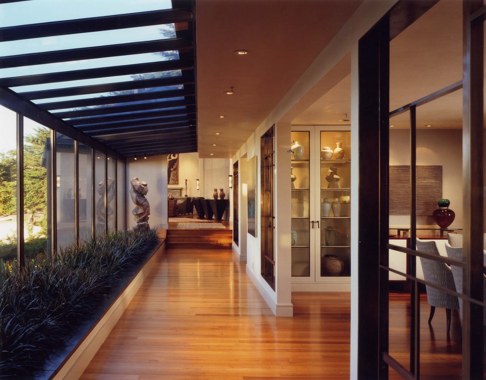 Modelo de recibidores y pasillos contemporáneos con suelo de madera en tonos medios