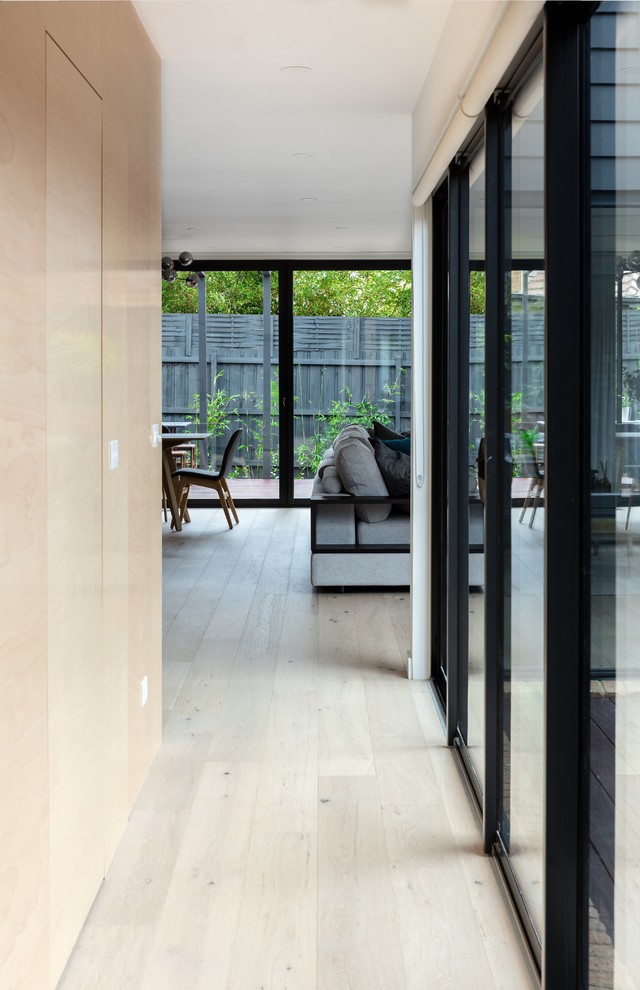 Modelo de recibidores y pasillos minimalistas de tamaño medio con paredes marrones, suelo laminado y suelo marrón
