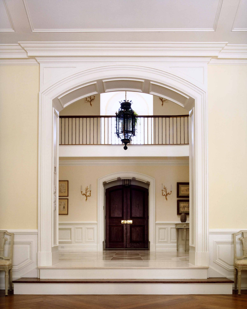 На фото: огромный коридор в классическом стиле с бежевыми стенами, паркетным полом среднего тона и коричневым полом с