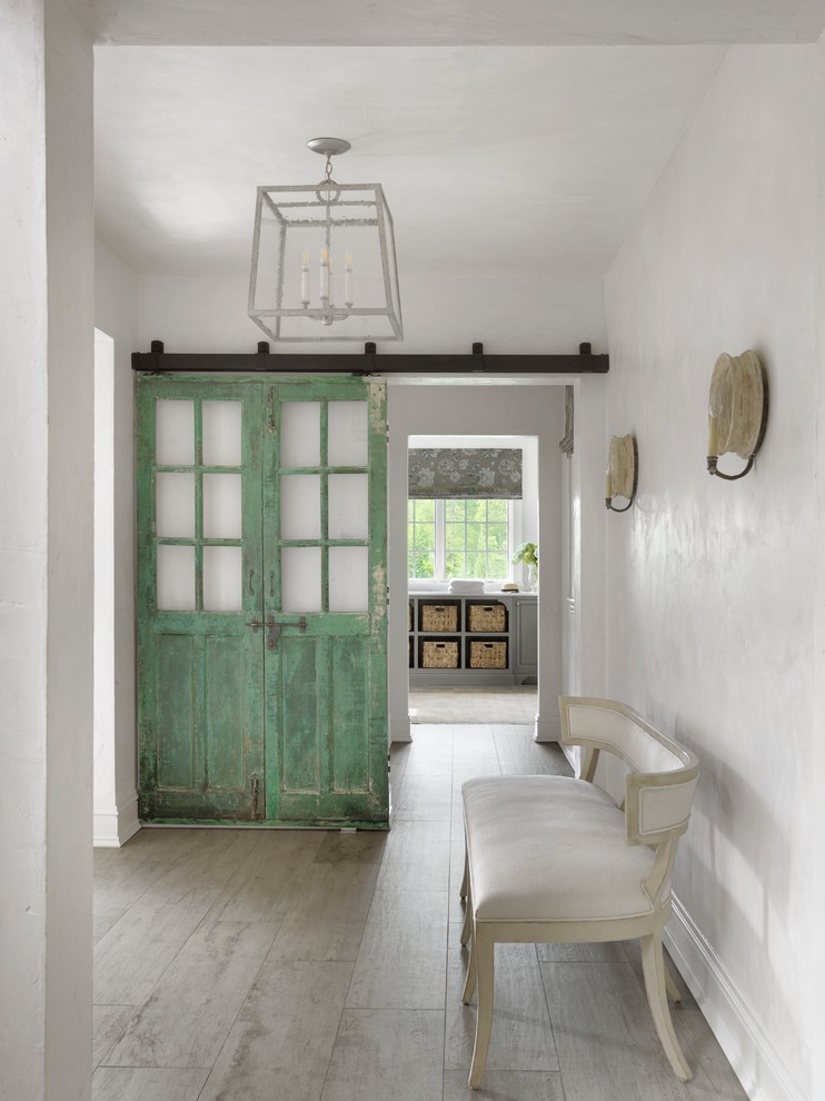 Bild på en lantlig hall, med vita väggar, ljust trägolv och grått golv