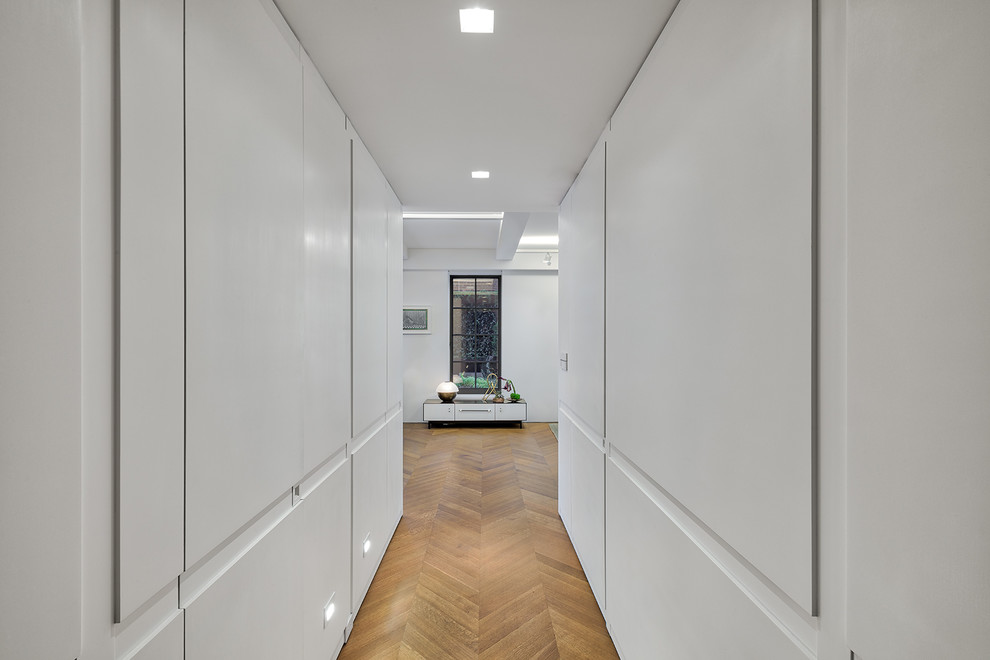 Imagen de recibidores y pasillos contemporáneos pequeños con paredes blancas, suelo de madera en tonos medios y suelo marrón
