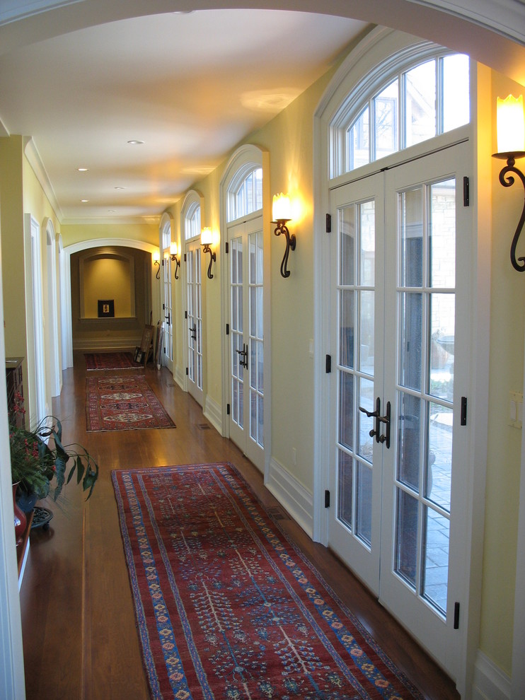 Cette image montre un grand couloir traditionnel avec un mur jaune et un sol en bois brun.