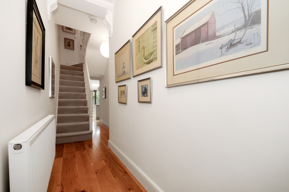 Immagine di un piccolo ingresso o corridoio minimal con pareti bianche e pavimento in legno massello medio