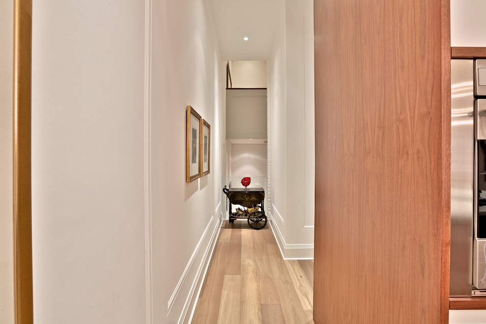 Large transitional medium tone wood floor hallway photo in Toronto with white walls