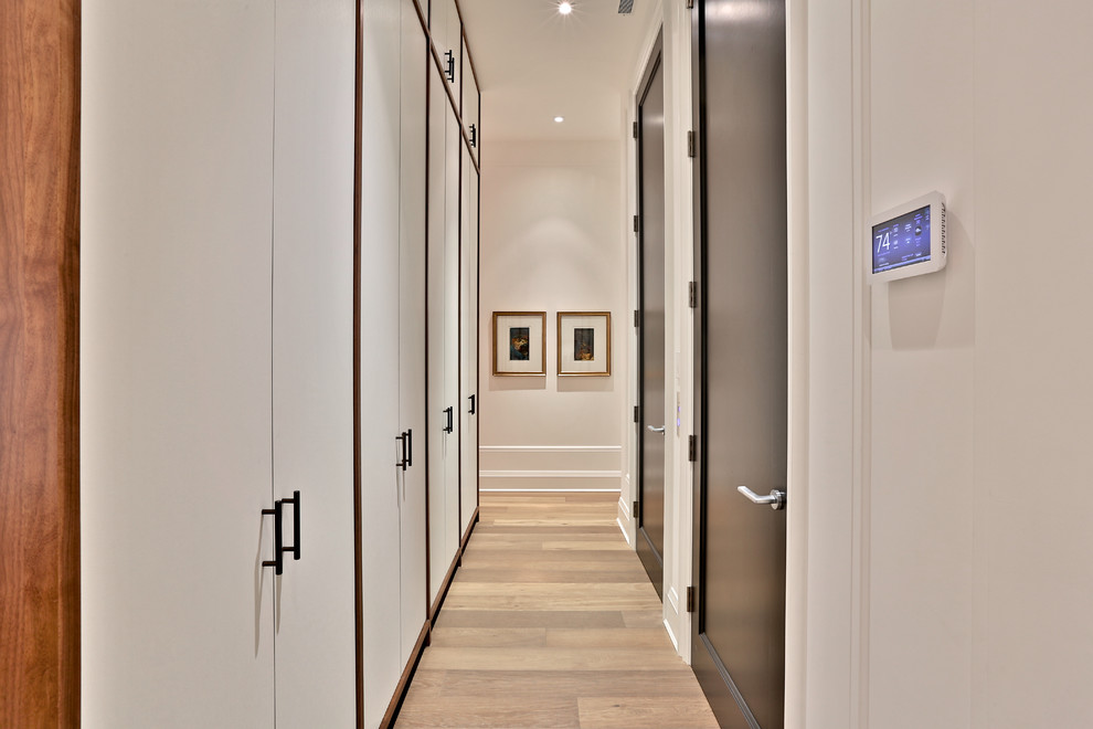 На фото: большой коридор в стиле неоклассика (современная классика) с белыми стенами и паркетным полом среднего тона