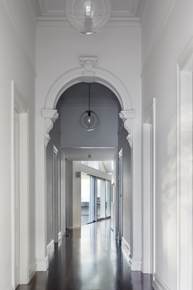 Immagine di un grande ingresso o corridoio minimal con pareti bianche, parquet scuro e pavimento marrone