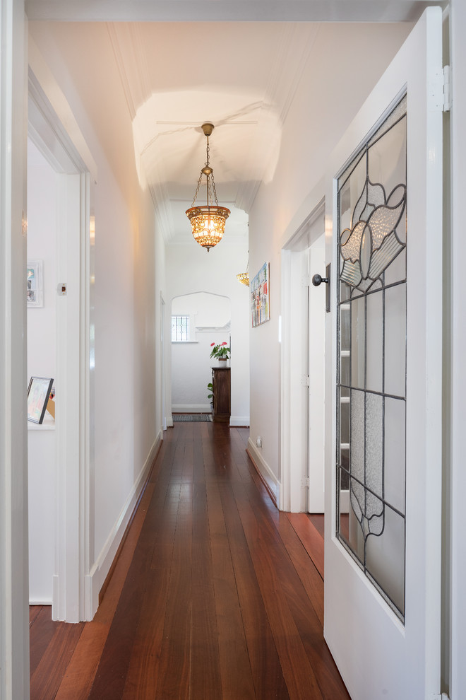 Aménagement d'un couloir classique avec un mur blanc, un sol en bois brun et un sol marron.