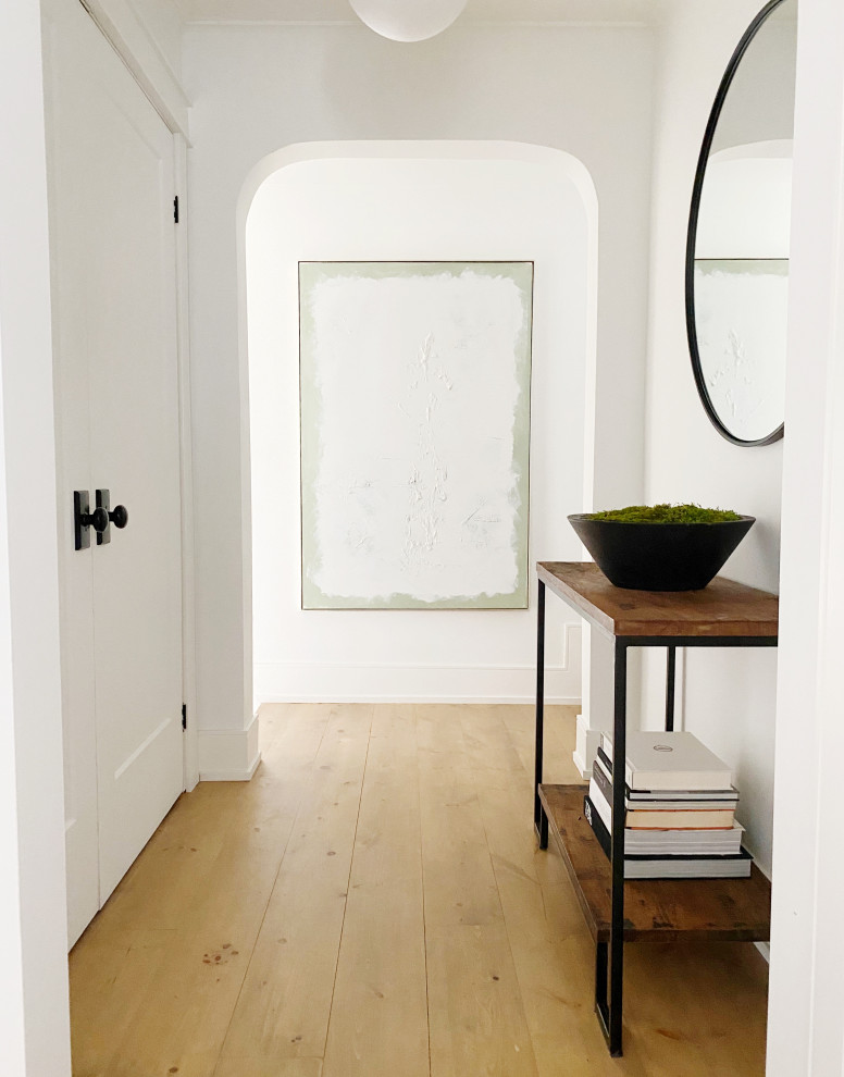 Example of a transitional light wood floor and beige floor hallway design in Toronto with white walls