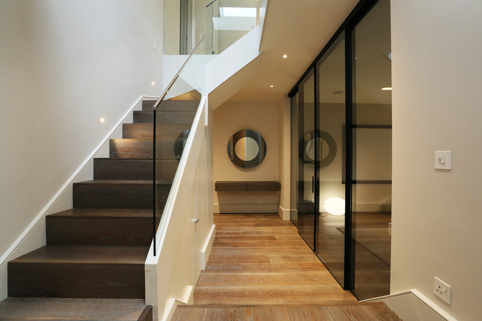 Cette photo montre un couloir tendance de taille moyenne avec un mur blanc et un sol en bois brun.