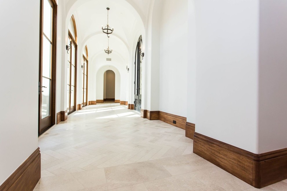 Lantlig inredning av en stor hall, med vita väggar, beiget golv och kalkstensgolv