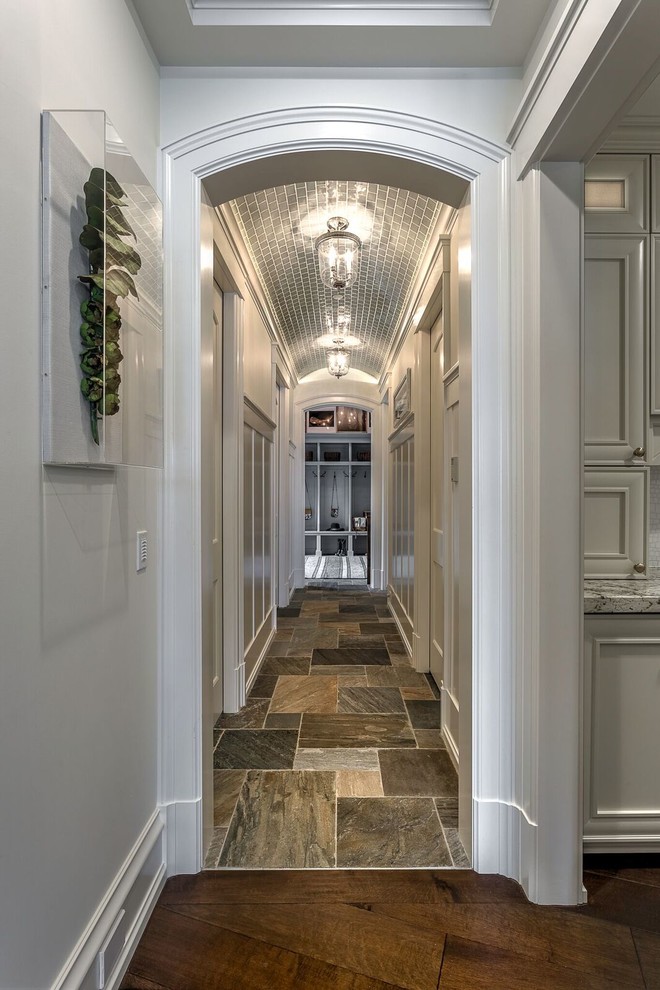 Aménagement d'un grand couloir classique avec un mur blanc, un sol en ardoise et un sol gris.