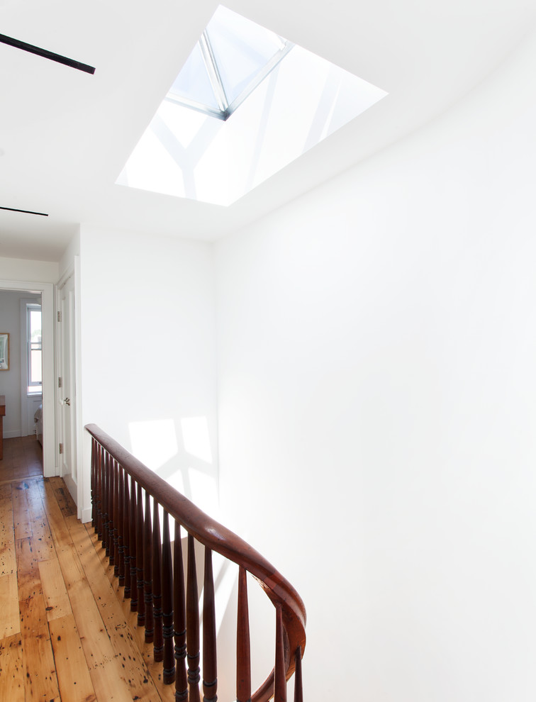 Großer Moderner Flur mit weißer Wandfarbe und braunem Holzboden in New York