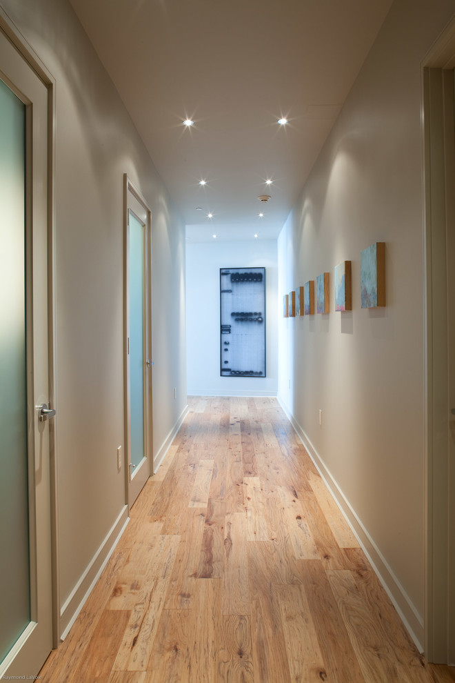Idée de décoration pour un couloir design de taille moyenne avec un mur beige et parquet clair.
