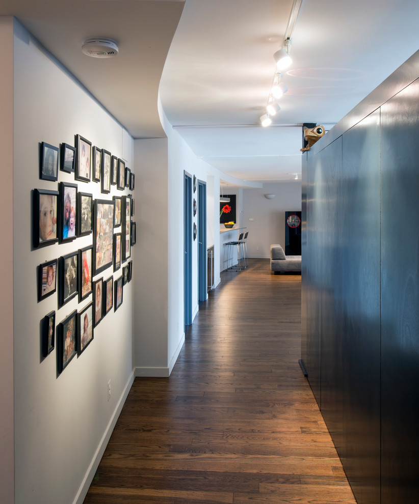 Idée de décoration pour un couloir design de taille moyenne avec un mur gris et un sol en bois brun.