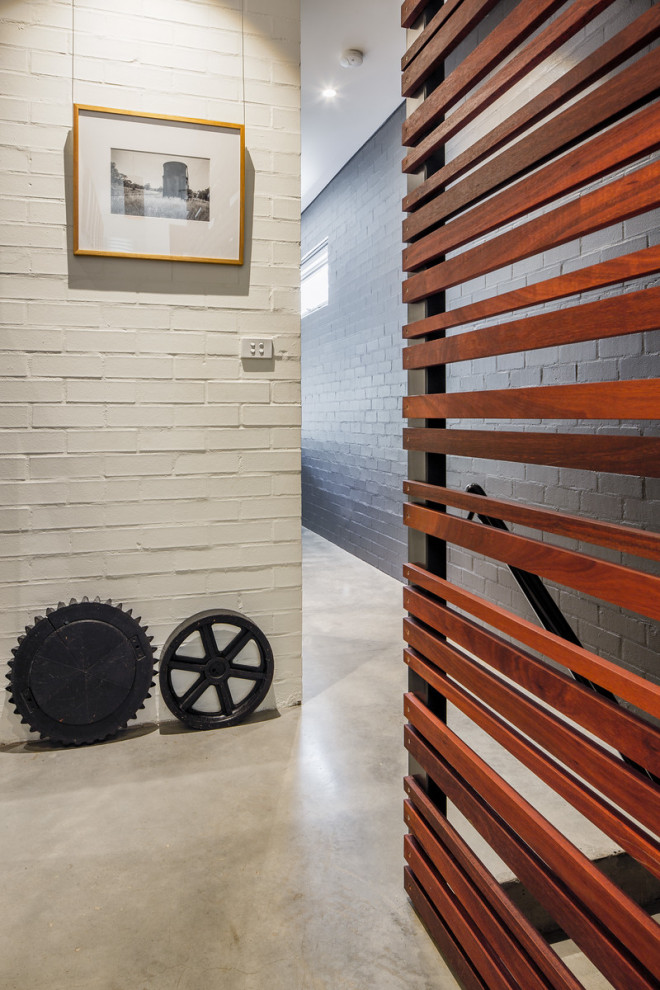 Inspiration for a mid-sized contemporary concrete floor, gray floor and brick wall hallway remodel in Newcastle - Maitland with white walls