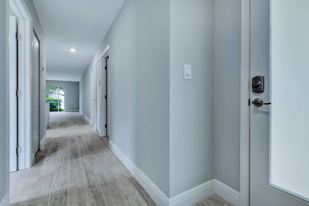 Inspiration pour un couloir design de taille moyenne avec un mur gris, parquet clair et un sol marron.