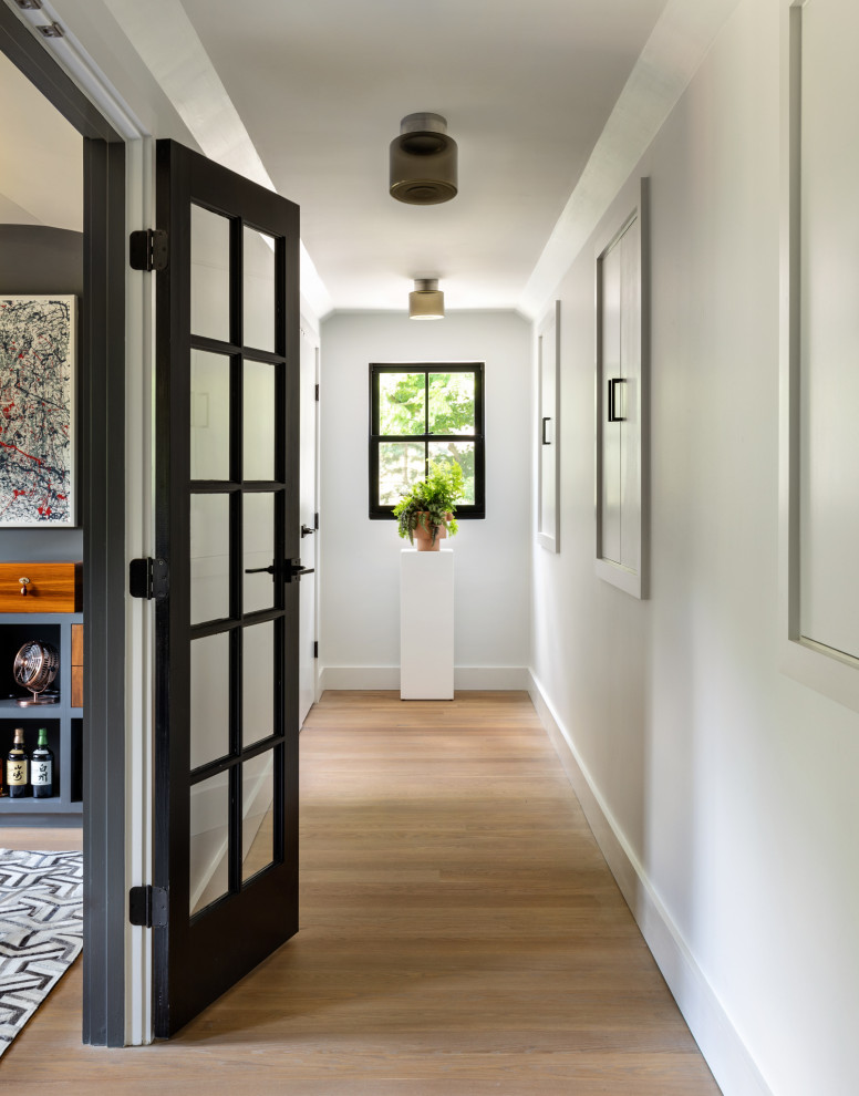 Kleiner Moderner Flur mit weißer Wandfarbe, hellem Holzboden und braunem Boden in New York