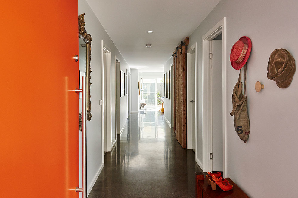 На фото: большой коридор в стиле неоклассика (современная классика) с оранжевыми стенами и бетонным полом с