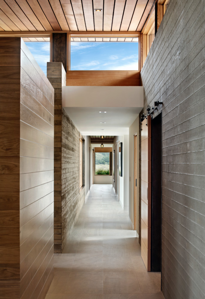 Cette photo montre un très grand couloir tendance en bois avec un mur multicolore, un sol gris et un plafond en bois.