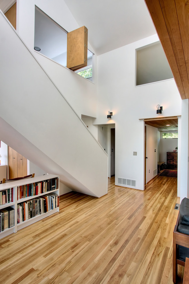Diseño de recibidores y pasillos minimalistas con paredes blancas y suelo de madera en tonos medios