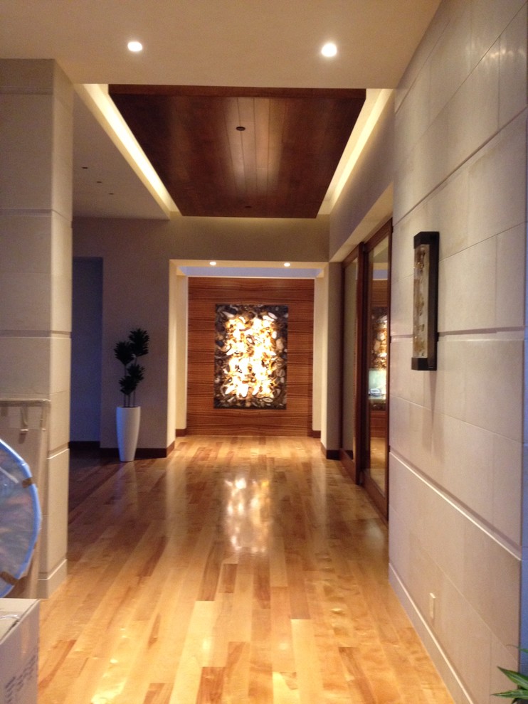 Inspiration pour un grand couloir design avec un mur beige et un sol en bois brun.