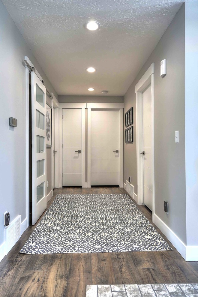 Idée de décoration pour un couloir design de taille moyenne avec un mur gris, sol en stratifié et un sol marron.