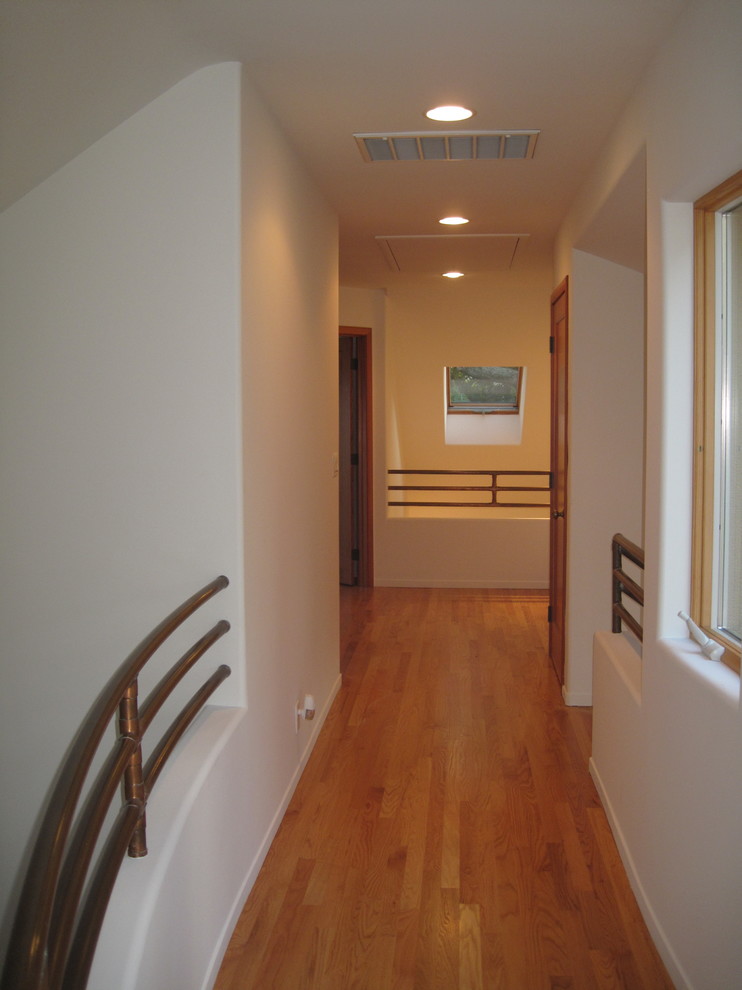 Esempio di un ingresso o corridoio minimal con pareti bianche e pavimento in legno massello medio