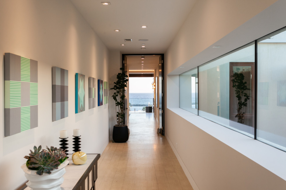 Hallway - large contemporary light wood floor and beige floor hallway idea in Orange County with white walls