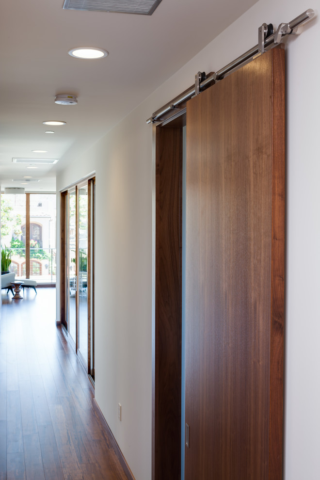 На фото: коридор среднего размера в стиле модернизм с белыми стенами и полом из бамбука с