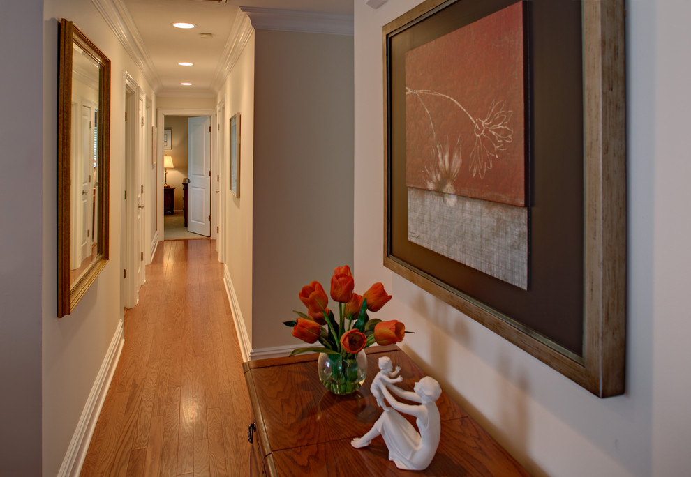 Cette photo montre un couloir chic de taille moyenne avec un mur beige et un sol en bois brun.