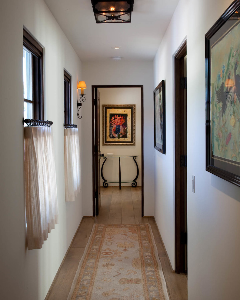 Example of a small tuscan medium tone wood floor hallway design in San Diego with white walls