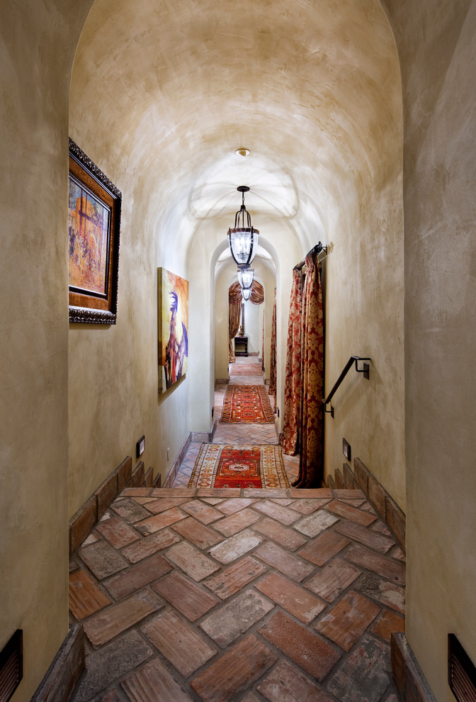 オースティンにある広い地中海スタイルのおしゃれな廊下 (ベージュの壁、レンガの床) の写真