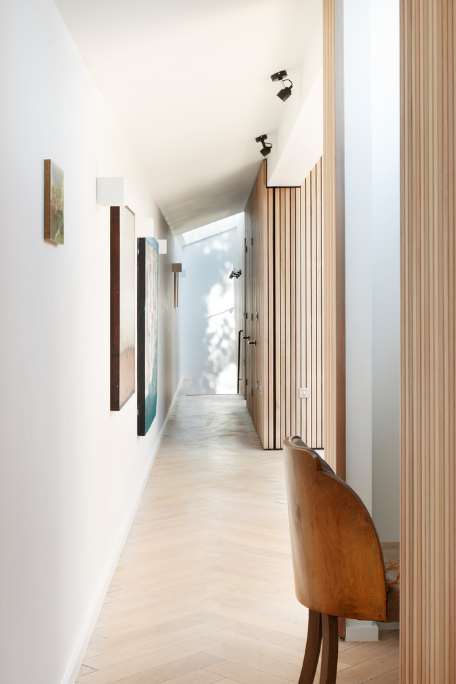 Inspiration pour un couloir design avec un mur blanc, parquet clair et un sol beige.