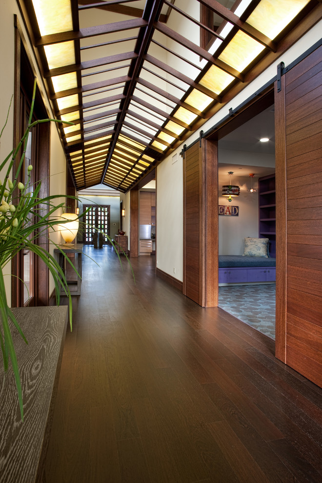 Réalisation d'un grand couloir asiatique avec un mur blanc, parquet foncé et un sol marron.