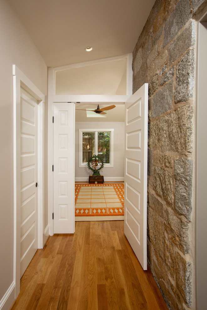 Cette photo montre un couloir chic de taille moyenne avec un mur beige, parquet clair et un sol marron.