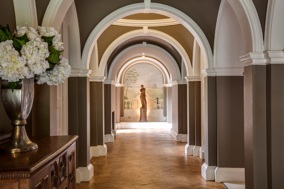Ejemplo de recibidores y pasillos clásicos con paredes marrones y suelo de madera en tonos medios