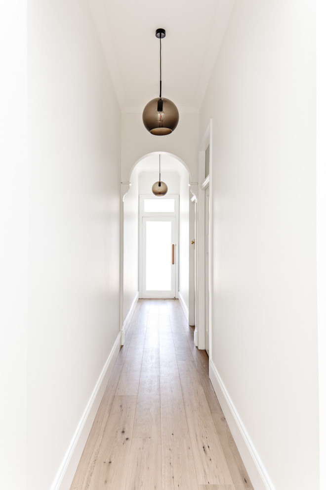 Imagen de recibidores y pasillos contemporáneos pequeños con paredes blancas y suelo de madera clara